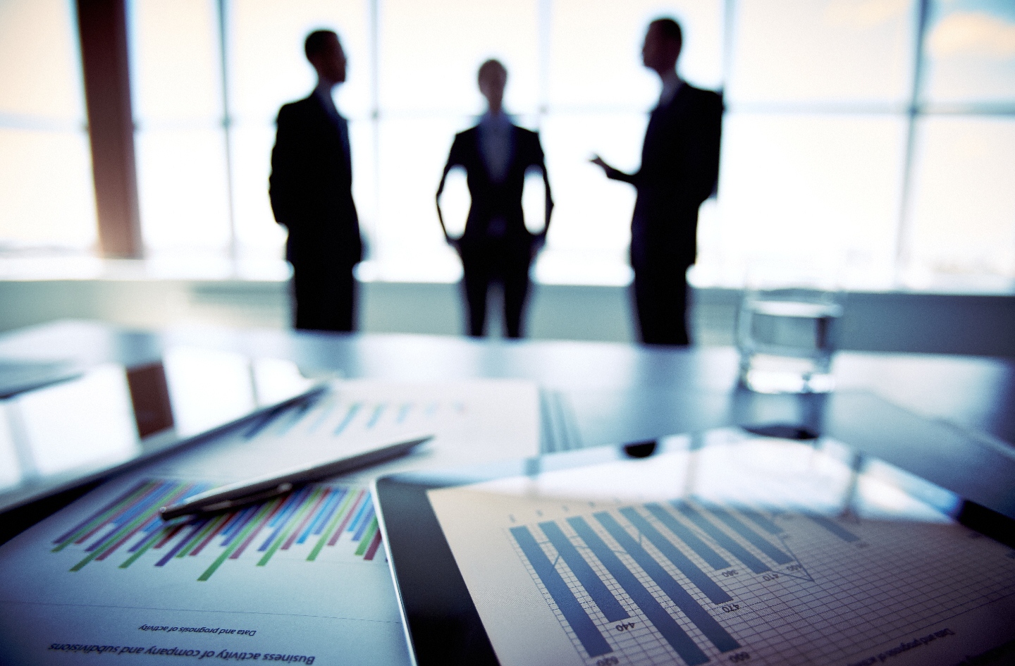charts on a table with three human silhouettes in the background